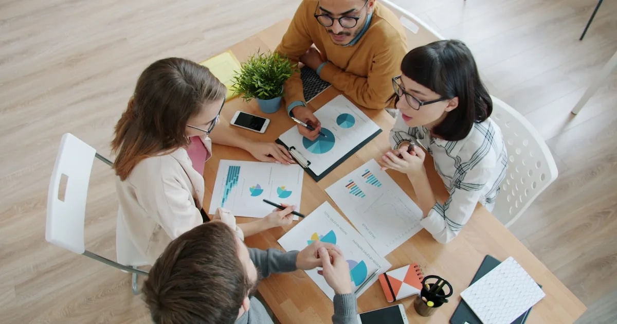 A small team reviews charts and business documents together during a data-driven strategy meeting