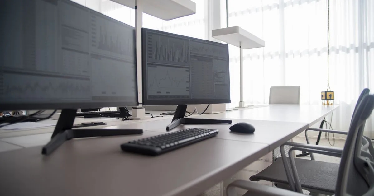 A modern office workspace with two computer monitors side by side on a desk