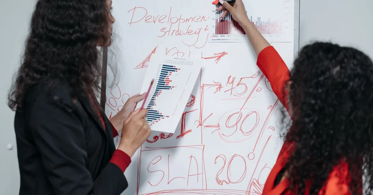 Two professional women discussing and planning business strategy in a modern office