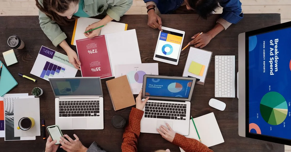 A diverse marketing team collaborating on advertising strategy using laptops and tablets